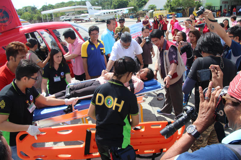 DOH-MIMAROPA Regional Director Eduardo C. Janairo with members of the rescue team of Kilos Agad Action Center (KAAC) of the Puerto Princesa City Health Office of Palawan and PAMAS staff receives a woman in labour from Brookespoint, Palawan during the launching and test run of the DOH-MIMAROPA Air Ambulance which will serve indigent and indigenous patients of the region.
