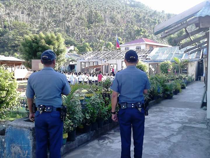 Two police personnel pays respect to the PH flag during the opening of class in Concepcion town. (Photo: Concepcion MPS)