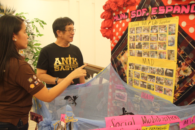 A representative of Pilipinas Shell Foundation, Incorporated shows Regional Director Eduardo C. Janairo the various anti-malaria activities done in the municipality of Sofronio Espaniola during the 2017 Malaria Congress in Puerto Princesa City, Palawan on November 29, 2017